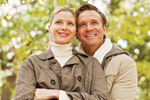 A young couple hold each other while looking at somthing in the distance. Links to Under Age 60 A young couple hold each other while looking at somthing in the distance. Links to Under Age 60